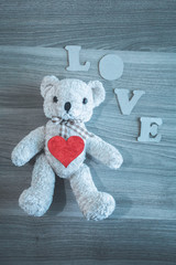 Teddy bear, LOVE letters, heart on wooden background. Place for text. The concept to St. Valentine.