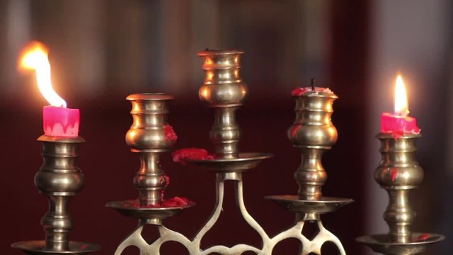 Color footage of two candles burning in a candlestick, fading out.