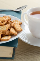 Cookies on old book and white cup of tea