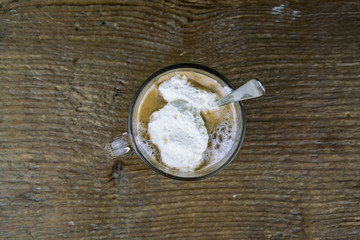 Single glass of freshly prepared coffee full of creme from top down view on wooden surface