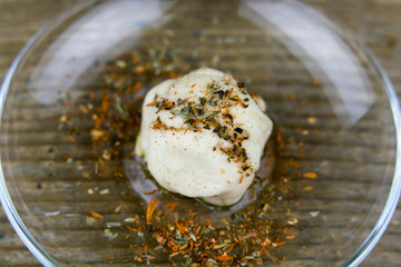 Close up view of raw bun with herbs placed in a small glass bowl on dark wooden table
