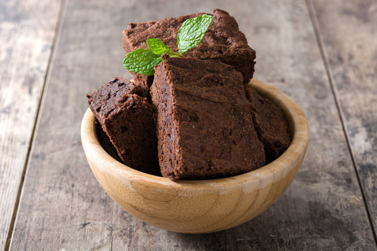 Chocolate brownie portions in bowl on wooden background
