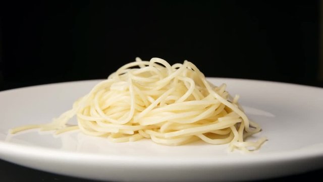 SLOW MOTION: Prepared spaghetti falls on a white dish