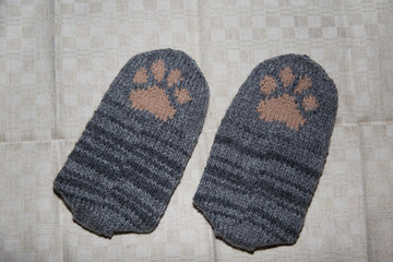 Pair of a hand knitted woolen socks with a cat paw pattern on linen background