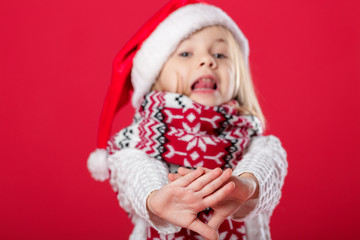 little girl in santa hat and scarf on red background