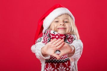 little girl in santa hat and scarf on red background