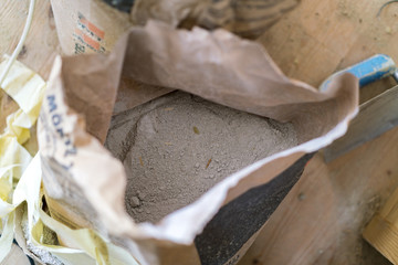 Opened bag of dry cement viewed from above on a building site in a construction or renovation...