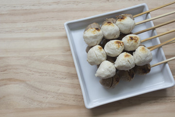 Pork meatballs on white plate placed on a wooden floor.