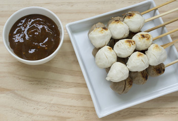 Pork meatballs on white plate placed on a wooden floor.