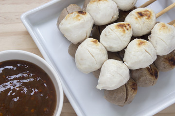 Pork meatballs on white plate placed on a wooden floor.