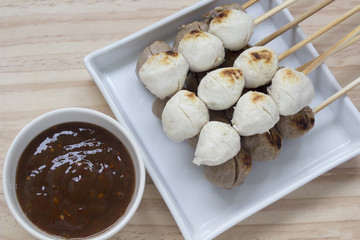 Pork meatballs on white plate placed on a wooden floor.