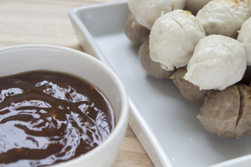 Pork meatballs on white plate placed on a wooden floor.