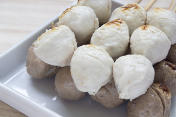 Pork meatballs on white plate placed on a wooden floor.