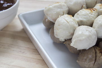 Fototapeta na wymiar Pork meatballs on white plate placed on a wooden floor.