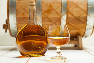 glass of cognac and a bottle on the background  the barrel
