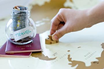 Travel budget - vacation money savings in a glass jar on world m