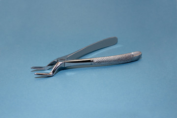 Dental pincers to remove the front teeth on blue background