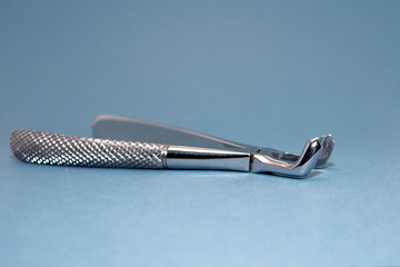 Dental pincers to remove the chewing teeth on blue background