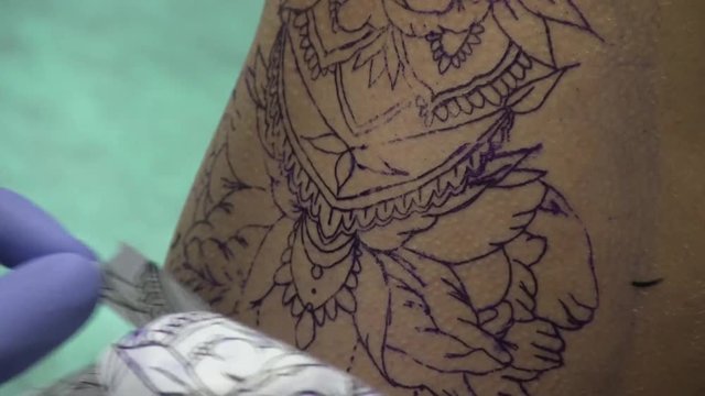 A Tattoo Artist Takes Away Tracing Paper After Transferring A Drawing To A Girl's Hip