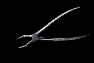 Obraz premium Dental pincers to remove the front teeth on black background