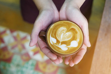 Top view of hands holding hot coffee latte cup with chain of hea