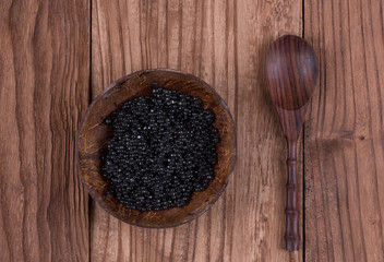 black caviar in a wooden plate, cutlery