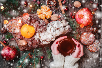 Fototapeta na wymiar Female hand a cup of tea. Christmas Cookies Chocolate, tea, pomegranate, Tangerines, Nuts, cocoa beans on wooden snowy background. Xmas and Happy New Year card. Top view, selective focus