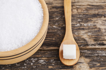 Wooden bowl and sugar on wooden background