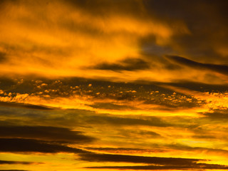 Dramatic golden sky with illuminated clouds at evening sunset time.