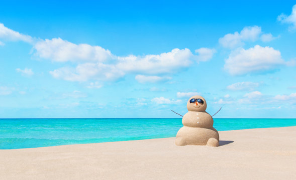 Positive sandy snowman in sunglasses at sunny tropical ocean beach