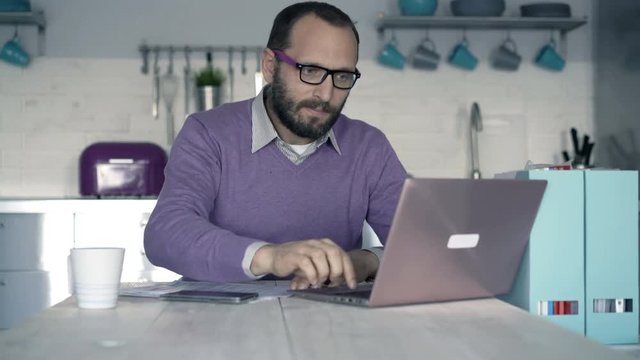 Young man finishing working on laptop and leaving office

