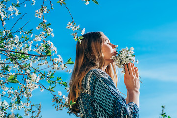 Portrait of young girl in blossom cherry garden, smelling a bouquet of flowers, closed eyes