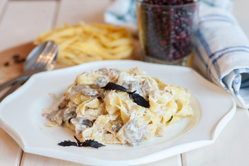 Fettuccine carbonara in a white bowl with bacon and mushrooms.