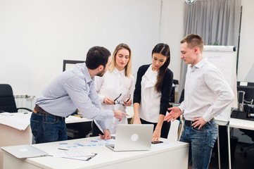 Colleagues at an office meeting talking and working on a laptop