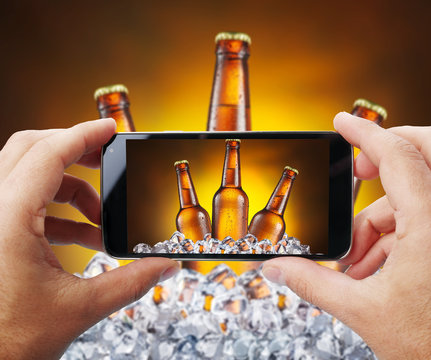 Taking photo of beer bottles in ice by smartphone.