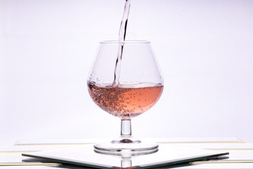 A backlit wine in a glass, Bright field lighting of a liquid in a glass, A liquid being poured into a glass
