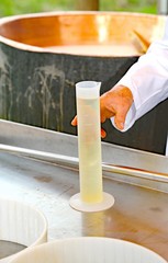 cheesemaker grab with the hand a plastic tube with the rennet to