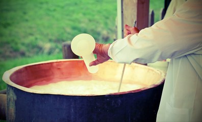 cook pours rennet into the warm cauldron to produce cheese