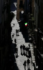 Italian flag and silhouettes of people in the narrow street