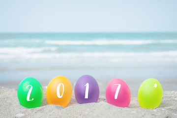 2017 text on colorful eggs on white sand beach over blue sea,happy Happy new year 2017  or Easter holiday concept.