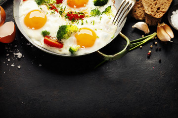 Pan of fried eggs, broccoli and cherry-tomatoes, top view
