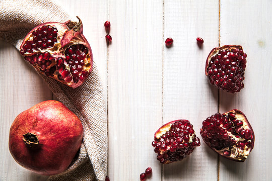 Ripe pomegranates, napkin and table knife on wooden background