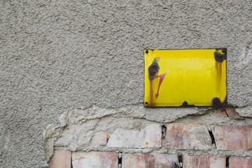 yellow metal plate on a brick wall