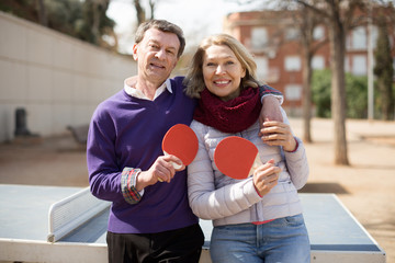 portrait of an elderly couple with rackets for table tennis