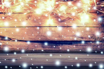 Christmas light, snow on wooden background and wooden table with
