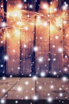 Christmas light, snow on wooden background and wooden table with