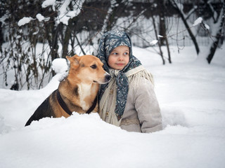 Little girl and dog sitting in snow drifts in the woods