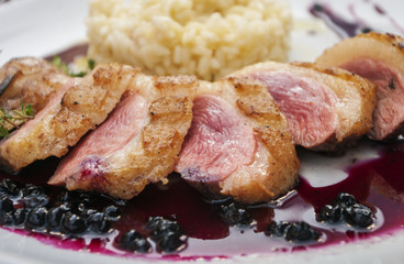Close up of grilled duck breast covered with sweet red fruit sauce.