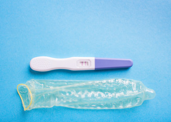 Pregnancy test positive with two stripes and a condom. Plastic c