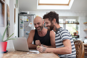 Gay couple using laptop in the kitchen